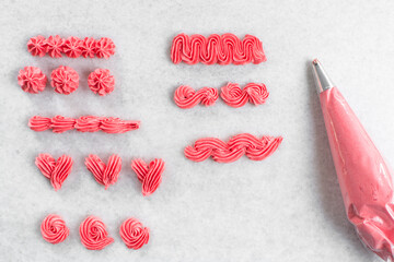 overhead view of Pink buttercream piped using a nozzle, buttercream piped using a small piping tip on a white countertop