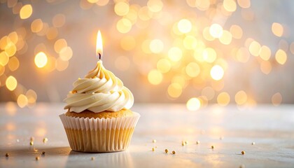 A single vanilla cupcake with white frosting and a lit candle, set against a warm, blurry background of golden bokeh lights.