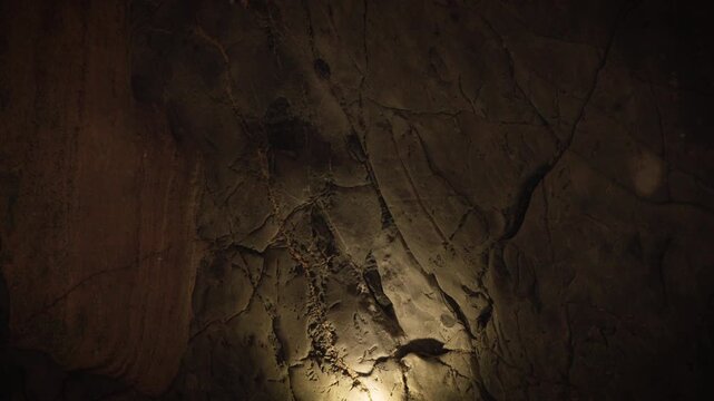 atural limestone cave texture with stalactites and stalagmites in darkness. Mysterious underground tunnel in Thailand.	
