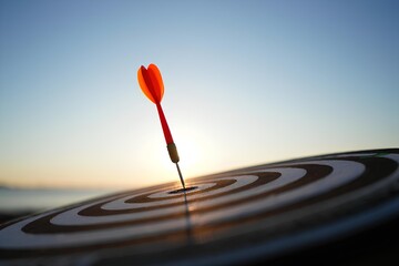 Accurate red dart arrow shot hitting bullseye on dartboard, business target success and goal achievement concept, strategy performance, competition skill, marketing idea closeup view