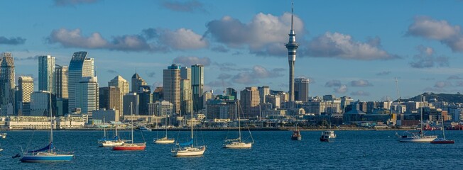 Auckland, New Zealand skyline view from the water. Sailboats are moored in the harbor. The Sky Tower is the tallest structure in the city. The photo shows the city's beauty.