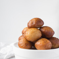 close up view of nigerian puff-puff on a white plate, nigerian fried dough balls, homemade bofrot on a white background