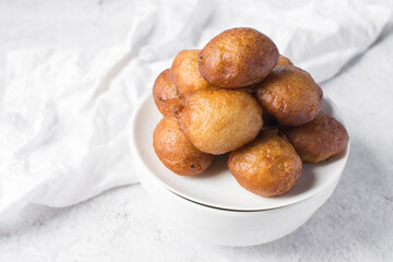 close up view of nigerian puff-puff on a white plate, nigerian fried dough balls, homemade bofrot on a white background