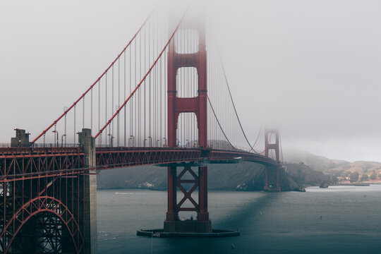 Golden Gate Bridge rising through the fog with soft light over the bay.
