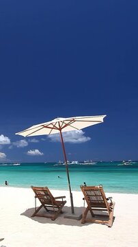 Sun umbrella and beach chairs on tropical beach. Summer vacation. Boracay. Vertical footage
