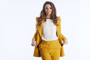 A businesswoman in a bright yellow suit shows her empty pockets with a perplexed expression, symbolizing financial concern, debt, or budgeting challenges in a clean studio setting.