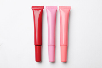 Different lip glosses on white background, flat lay