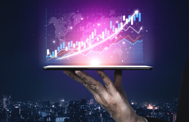 A professional hand holding a tablet showcasing vibrant digital graphs and charts, symbolizing growth in finance and technology in a modern urban setting. Impute