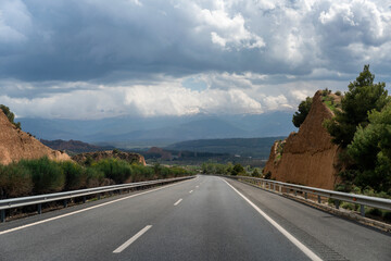 Highway winding through mountains in Spain under cloudy sky