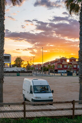 Camper van on a residential area with buildings with sunset on the background