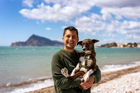 Man holding a brown dog on his lap while smiling at the camera