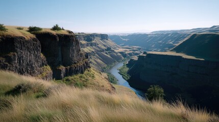 Breathtaking View of Canyon Landscape with River Flowing Through Lush Green Fields and Jagged Cliffs Under Clear Blue Sky