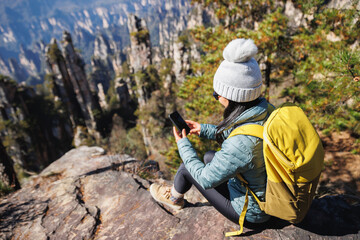 Female tourist taking selfie with smart phone hiking in mountains