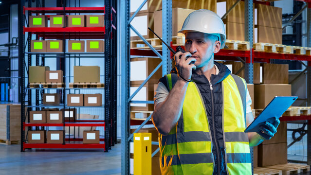 Warehouse logistics coordination as a worker with a radio and tablet manages inventory shelves, oversees parcel handling, and monitors storage operations for efficient workflow.