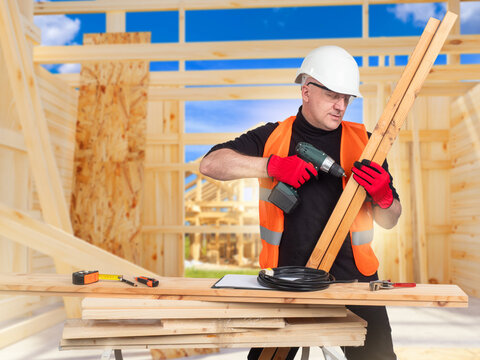 Carpentry construction worker drills wooden beams, assembling framework and preparing structural elements during residential building work on site. - Powered by Adobe