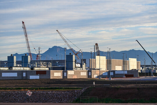 Large data center campus with completed buildings and active construction zones, featuring cranes, structural modules, and utility infrastructure supporting high-capacity digital operations