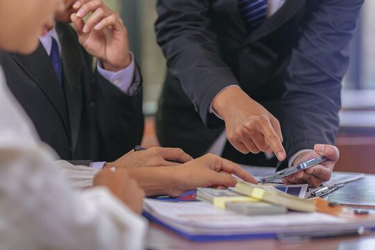 Business peoples using smartphone, meeting to discuss the situation on stock market, talking business plan for investment. Selected focus