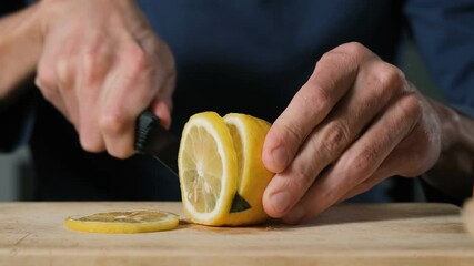 Close-up of slicing a juicy fresh lemon on a cutting board, preparation of a healthy vitamin drink for wellness and morning energy concept