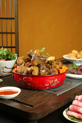 Traditional Asian Lamb Stew with Bone-in Meat in Red Ceramic Pot Hot Pot Style Dining Setup