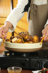 Chef Serving Hot Lamb Stew with Potatoes from Ceramic Pot on Kitchen Stove