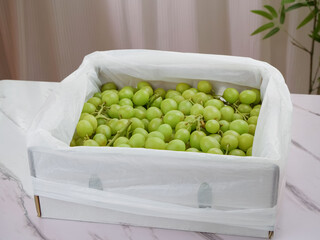 Fresh Green Seedless Grapes in White Wooden Crate on Marble Counter