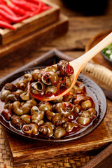 Spicy Braised Whelk Meat in Traditional Ceramic Bowl with Wooden Spoon - Asian Seafood Cuisine