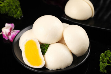 Steamed Buns with Golden Egg Yolk Filling on Black Plate with Orchid Garnish