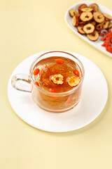 Cornhusk herbal tea with dried fruits and goji berries in glass cup on white saucer