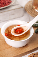 Traditional Chinese Herbal Tea with Goji Berries and Cornhusk Silk in White Bowl on Wooden Board