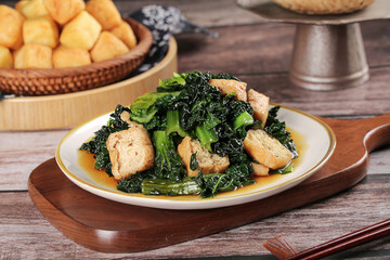 Asian Stir-Fried Leafy Greens with Tofu Puffs - Healthy Vegetarian Dish on Wooden Table