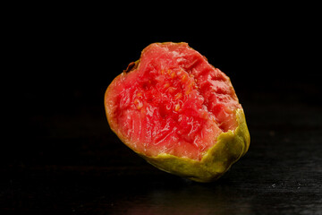 Fresh Pink Guava Fruit Half Showing Sweet Flesh and Seeds on Dark Wood Surface