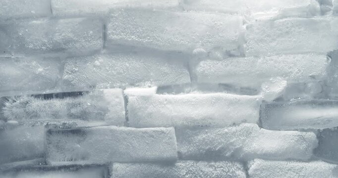 Timelapse of frozen ice blocks thawing. Wall of ice cubes covered with white frost warming and melting. Freezing cold wintery theme or wintertime backgrounds.