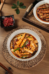 Asian Bacon Stir-Fry with Vegetables in Ceramic Bowls on Wooden Table with Chopsticks and Chili Garnish