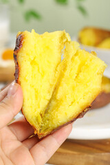Hand Holding Fresh Baked Golden Kintoki Sweet Potato Slice with Fluffy Yellow Interior