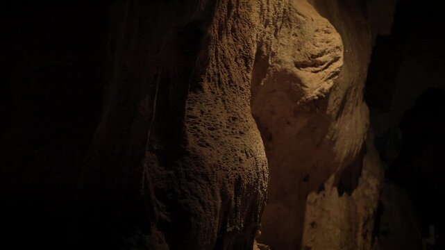 Natural limestone cave texture with stalactites and stalagmites in darkness. Mysterious underground tunnel in Thailand.