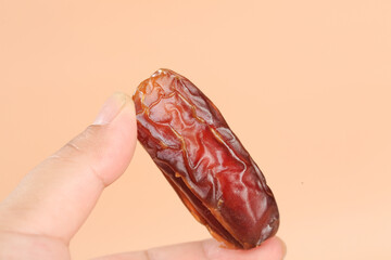 Hand Holding Fresh Dried Date Fruit on Golden Background - Middle Eastern Healthy Snack