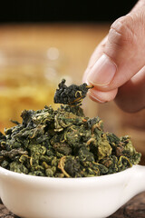 Hand Selecting Dried Mulberry Leaves for Healthy Herbal Tea Recipe in White Bowl