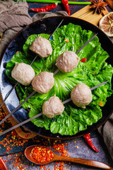 Round beef meatballs on skewers with lettuce in cast iron pan - Asian cuisine cooking