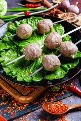 Round beef meatballs on lettuce leaves in cast iron pan with Asian spices and fresh vegetables for healthy cooking