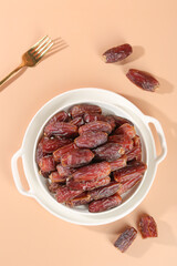 Dried Dates in White Bowl with Golden Fork - Traditional UAE Middle Eastern Fruit Snack on Peach Background