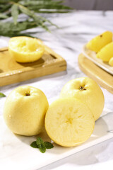 Fresh Yellow Apples Whole and Sliced on Marble Surface with Mint Garnish