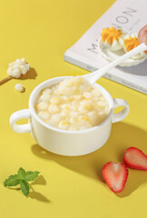 Fresh White Glutinous Corn Soup Bowl with Strawberry and Mint on Yellow Background