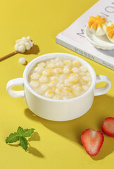 Sticky corn grain soup in white bowl with fresh garnishes on yellow background for healthy cooking