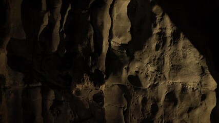 Natural limestone cave texture with stalactites and stalagmites in darkness. Mysterious underground tunnel in Thailand. - Powered by Adobe