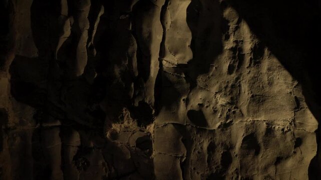 Natural limestone cave texture with stalactites and stalagmites in darkness. Mysterious underground tunnel in Thailand.
