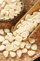 Blanched Almond Slices and Peeled Almonds in Wooden Spoon on Bamboo Mat