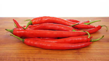 Several fresh red chilies lie on a brown wooden chopping board.