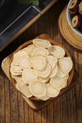 Fototapeta premium Changbaishan Ginseng Root Slices Traditional Chinese Medicine Health Supplement in Wooden Bowl