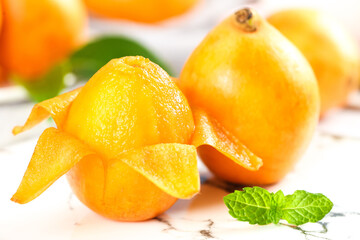 Fresh Loquat Fruits Peeled Showing Golden Flesh with Mint Garnish on White Wood Background
