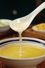 Pouring Golden Cooking Oil from Ceramic Spoon into Bowl - Kitchen Culinary Concept